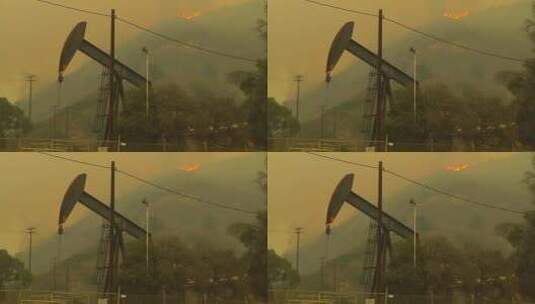 石油井架后的山在起火高清在线视频素材下载