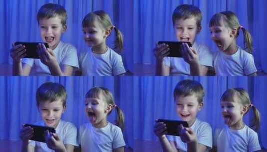 孩子们兄弟姐妹在黑暗中对着手机摄像头嬉笑高清在线视频素材下载