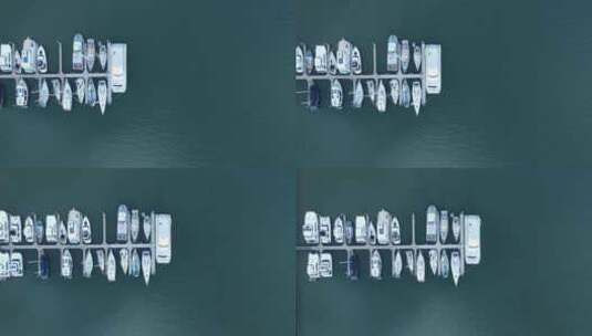 一架无人驾驶飞机俯视着停靠在码头上的多艘船只，码头位于一个受保护的港口高清在线视频素材下载
