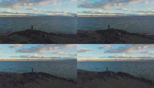 航拍黄昏时分一个人站在纳木错湖边的石头上高清在线视频素材下载