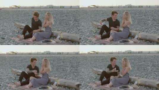 情侣坐在岩石沙滩聊天高清在线视频素材下载