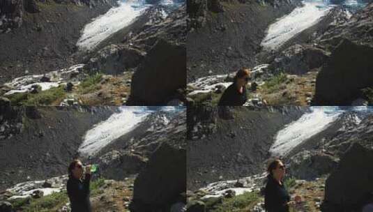 女孩正在冰川附近的高山徒步旅行，用瓶子喝高清在线视频素材下载