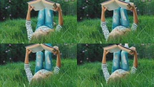 快乐的女孩躺在草地上阅读书籍高清在线视频素材下载