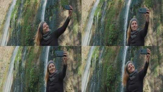 女人开心的用手机与瀑布合照高清在线视频素材下载