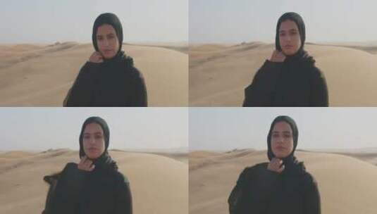 穆斯林女人在多风的沙漠中看着相机高清在线视频素材下载