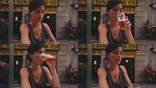 美丽的高加索女人在马德里（西班牙）的一家酒吧喝啤酒。坐在露台上的西班牙女孩高清在线视频素材下载
