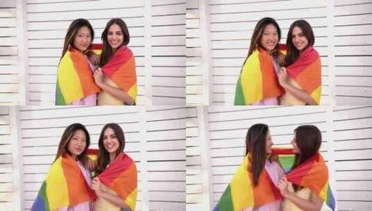 女同性恋夫妇一边看着相机一边用彩虹旗拥抱高清在线视频素材下载