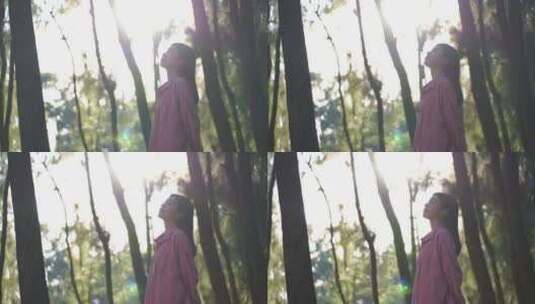 阳光下美女站在森林里感受自然的女孩抬头看高清在线视频素材下载