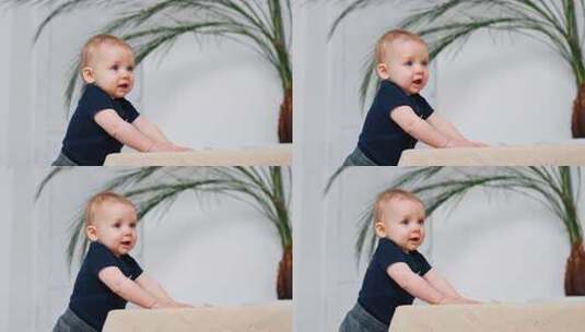 可爱的红头发男婴抱着沙发站着。可爱的小婴高清在线视频素材下载
