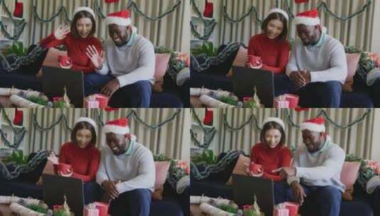 戴着圣诞帽的快乐多样化夫妇在家打圣诞笔记本电脑视频电话的视频高清在线视频素材下载