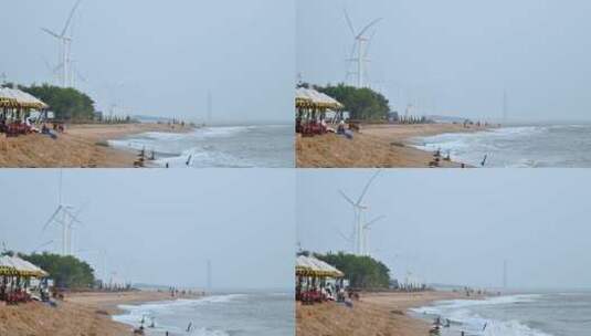 东方市鱼鳞洲沙滩上的游客与风力发电机。高清在线视频素材下载