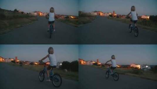 背景是村庄灯的空旷乡村道路上骑自行车的儿童男孩高清在线视频素材下载