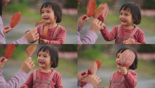可爱小女孩拿着秋天的树叶和妈妈玩耍高清在线视频素材下载