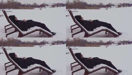 男人在雪地的躺椅上休息高清在线视频素材下载