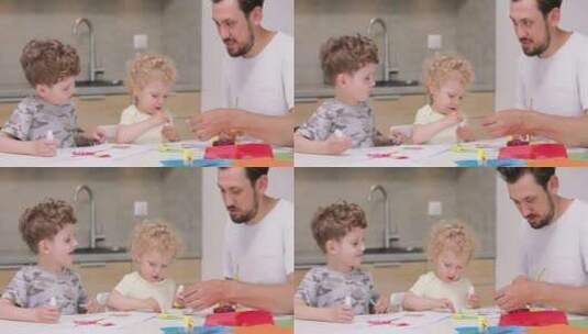 小女孩和小男孩正在用彩纸和胶水和他们的父亲做应用高清在线视频素材下载