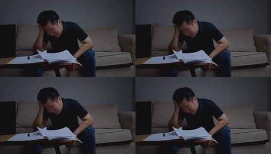 男人沙发前伏案处理文件高清在线视频素材下载
