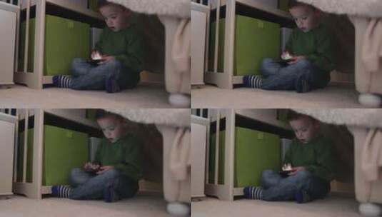 男孩盘腿坐在地毯上玩手机高清在线视频素材下载