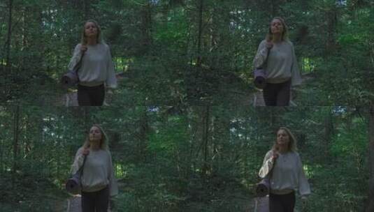 女人拿着瑜伽垫在树林里行走高清在线视频素材下载