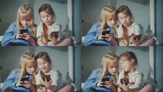 两个女孩并排坐在卧室的床上玩智能手机高清在线视频素材下载