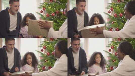 圣诞树旁给小孩礼物的父母高清在线视频素材下载