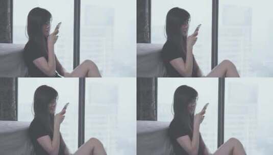 女孩开心地坐在窗边对着手机说语音高清在线视频素材下载