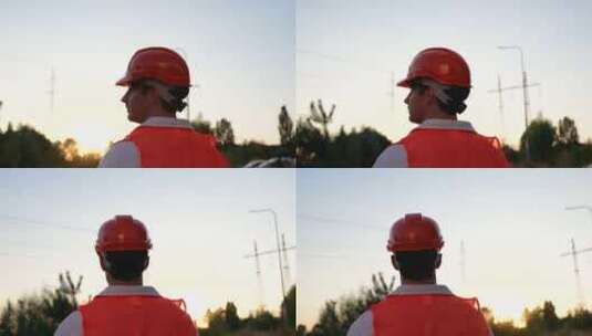 戴安全帽的男电工站在户外靠近高压电线最高高清在线视频素材下载