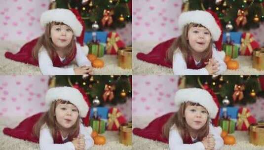 戴着圣诞帽躺在地毯上的小女孩高清在线视频素材下载