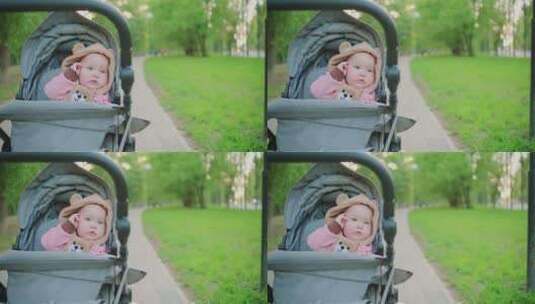公园里婴儿车里可爱的蹒跚学步的女孩的肖像高清在线视频素材下载