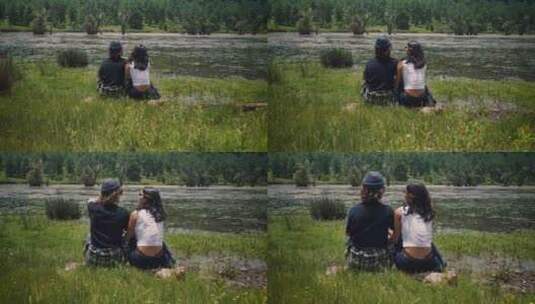 情侣坐在草地小河边背影高清在线视频素材下载