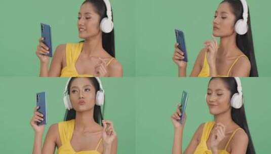 女孩拿着手机戴着耳机享受音乐高清在线视频素材下载