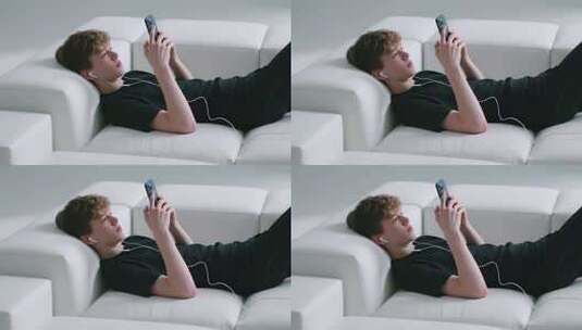 男子躺沙发上玩手机高清在线视频素材下载