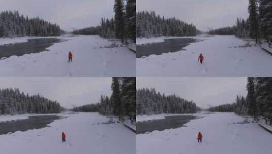 航拍男人艰难地走在新疆喀纳斯河边的雪地里高清在线视频素材下载