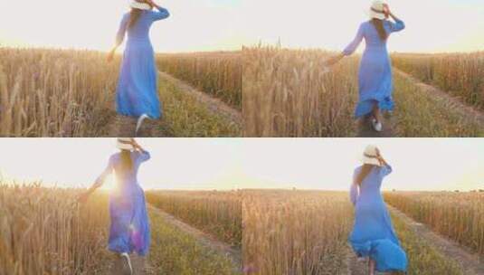 穿着蓝色连衣裙戴着帽子的美丽女人在日落时跑过麦田。自由概念。小麦高清在线视频素材下载