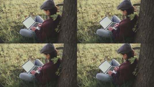 女人坐在草地上使用笔记本电脑高清在线视频素材下载