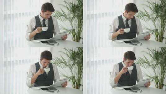 帅哥坐在桌边喝咖啡看报纸高清在线视频素材下载