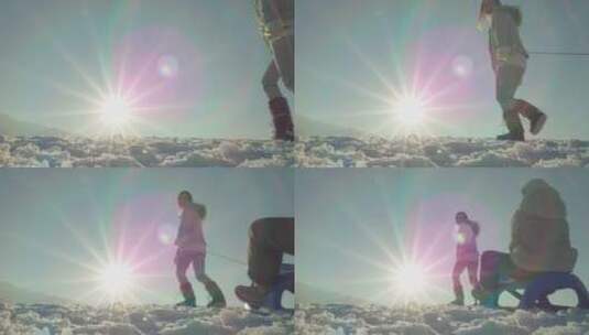 母亲拉着雪橇上的女儿在雪地里玩耍高清在线视频素材下载