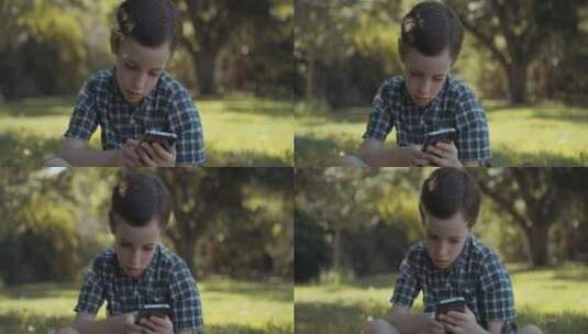 草地上玩手机的男孩高清在线视频素材下载