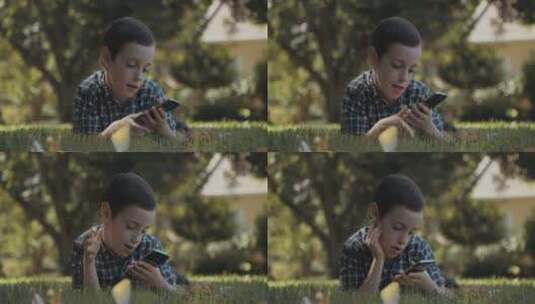 男孩在草地上玩手机高清在线视频素材下载