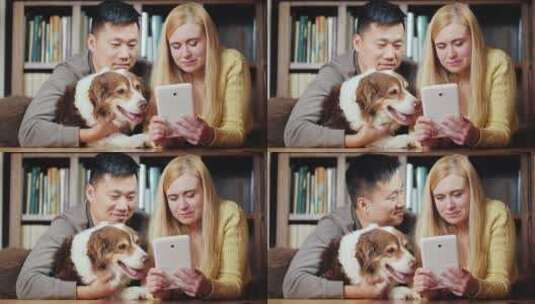 夫妇与狗在地板上看平板电脑高清在线视频素材下载