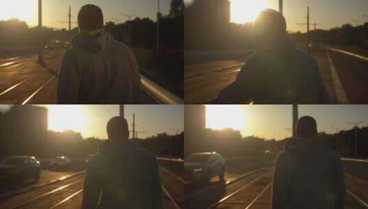年轻男性在夕阳下穿过电车线。慢动作，跟随高清在线视频素材下载