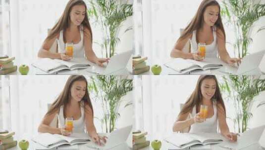 女人边用笔记本电脑工作边喝果汁高清在线视频素材下载