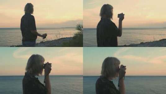 年轻的金发女子用模拟相机拍摄日落大海。高清在线视频素材下载