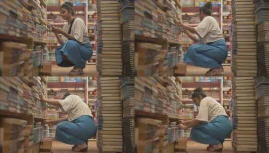 亚洲女孩坐着，通过书架探索书籍，侧角拍摄高清在线视频素材下载