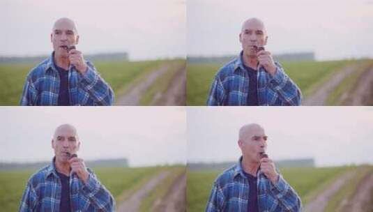满意的秃头农民在田野上抽烟斗高清在线视频素材下载