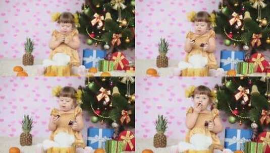 女孩在圣诞树旁吃糖果高清在线视频素材下载