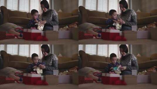 男孩和妈妈坐在客厅里拆礼物高清在线视频素材下载