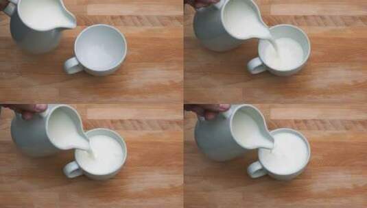 在木制背景的白色杯子里倒牛奶的特写。高清在线视频素材下载