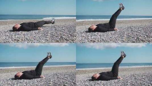 男孩在海边的海滩上用腿锻炼下腹肌高清在线视频素材下载