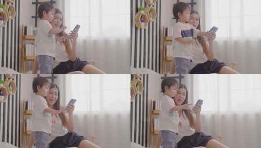 亚洲母亲在床上和孩子一起享受乐趣使用手机高清在线视频素材下载
