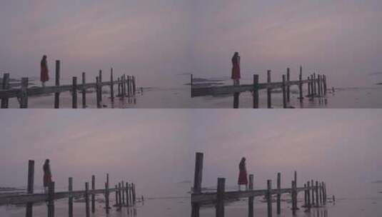 海边独走在木桥上的穿红裙子的女孩走向大海高清在线视频素材下载